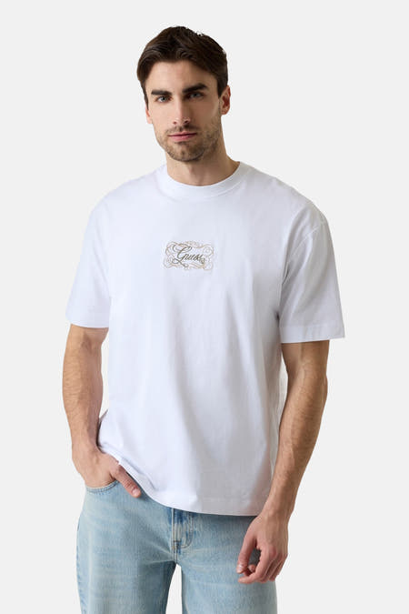 Witte korte mouwen T-shirt van Guess® met goudkleurig logo op borst, gedragen door model in lichte jeans, front view