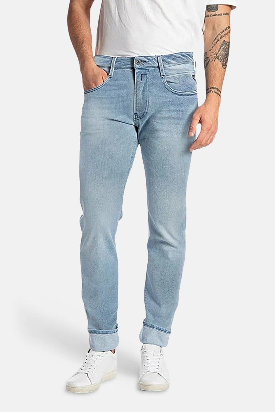 Jean slim fit bleu clair en denim de Replay, avec ourlets retroussés, combiné avec des baskets blanches et un t-shirt blanc.