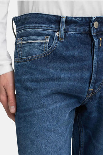 Donkerblauwe rechte jeans van REPLAY, close-up van de voorkant met zakken en knoop.