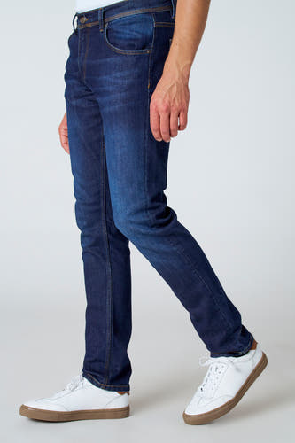 Jean slim fit en denim bleu marine de Le Fabuleux Marcel de Bruxelles, avec des baskets blanches en cuir.