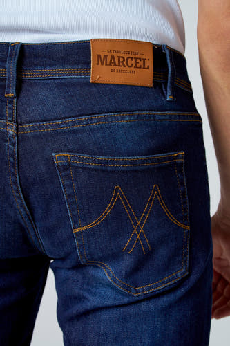Jean slim fit bleu marine de Le Fabuleux Marcel de Bruxelles, avec des boutons caractéristiques sur la poche arrière et un étiquette en cuir.
