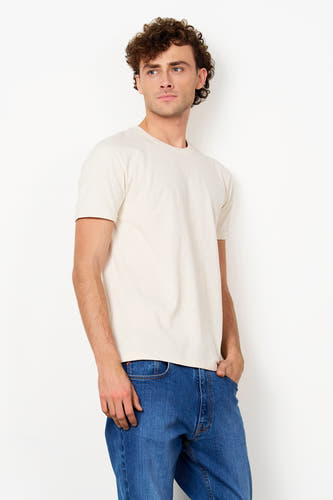 Ecru T-shirt van Le Fabuleux Marcel de Bruxelles, met korte, opgerolde mouwen en ronde hals, gedragen door een man.