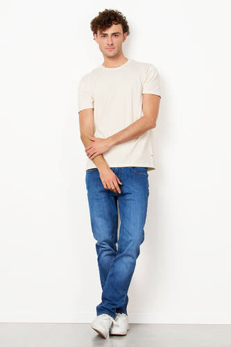 T-shirt blanc de Le Fabuleux Marcel de Bruxelles, à manches courtes, associé à des jeans bleus et des baskets blanches.