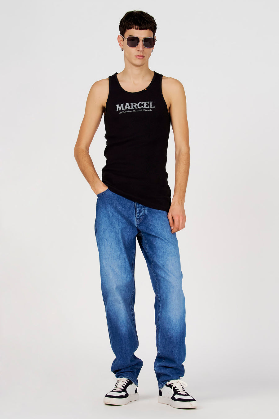 Zwarte tanktop van Le Fabuleux Marcel de Bruxelles, gedragen met jeans en zwart-witte sneakers.