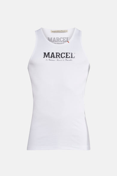Débardeur blanc de Le Fabuleux Marcel de Bruxelles, avec une texture côtelée et porté avec un pantalon marron.
