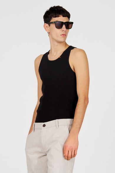 Zwarte tanktop van Le Fabuleux Marcel de Bruxelles, met een ribgebreide textuur, gedragen met een beige broek en zonnebril.
