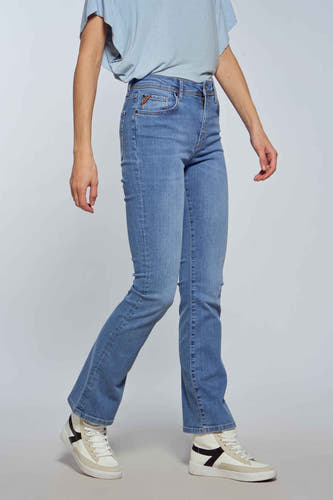 Jean bootcut bleu clair de Le Fabuleux Marcel de Bruxelles, avec lavage clair et porté avec des baskets blanches.