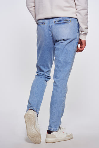 Jeans en denim bleu clair de Le Fabuleux Marcel de Bruxelles, vue arrière, avec des baskets blanches et un pull en couleur crème.
