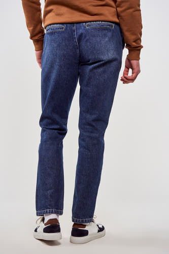 7/8 jeans en denim bleu de Le Fabuleux Marcel de Bruxelles, vus de dos, avec des baskets blanches.