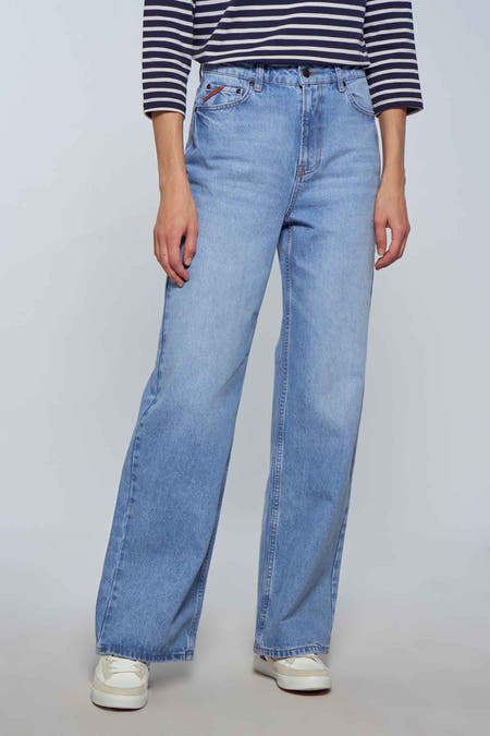 Wijd model jeans in lichtblauw denim van Le Fabuleux Marcel de Bruxelles, met een gestreepte top en witte sneakers.
