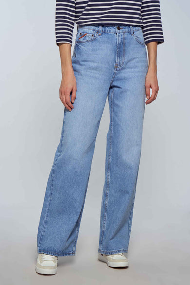 Jean large modèle en denim bleu clair de Le Fabuleux Marcel de Bruxelles, avec un haut rayé et des baskets blanches.