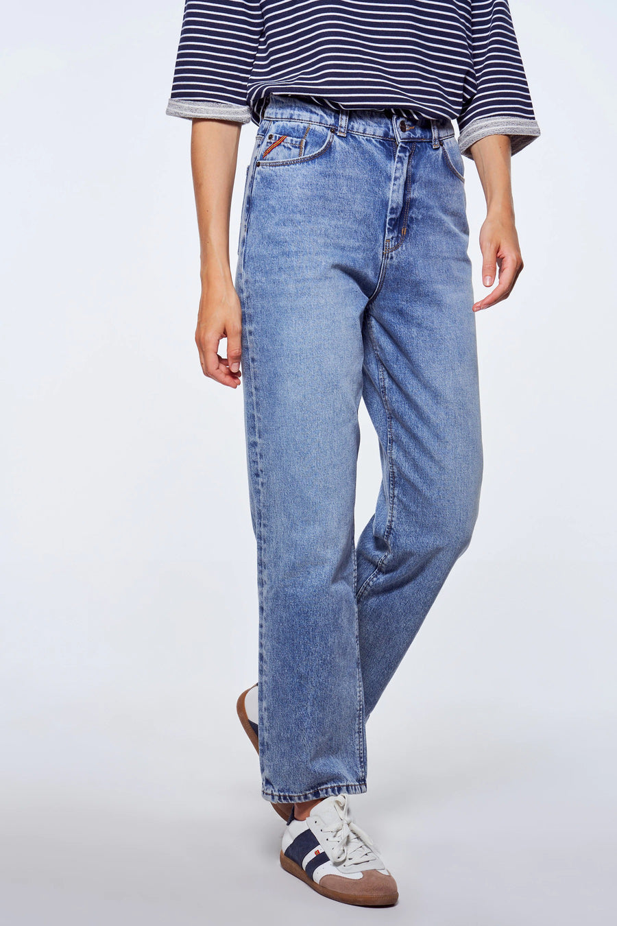 Rechte jeans van midblauw denim van Le Fabuleux Marcel de Bruxelles, gedragen met gestreepte top en sneakers.
