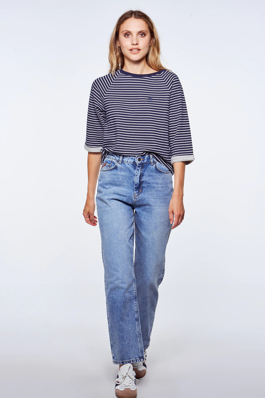 Blauwe rechte jeans van Le Fabuleux Marcel de Bruxelles, gecombineerd met gestreepte top en sneakers.
