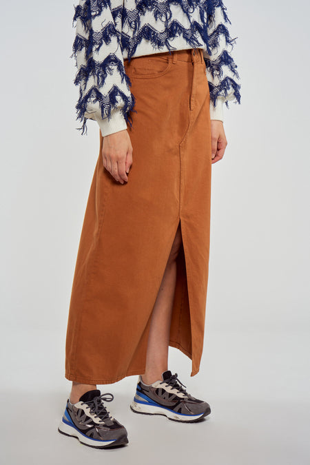 Bruine lange rok van Le Fabuleux Marcel de Bruxelles, met een split aan de voorkant en gecombineerd met kleurrijke sneakers.
