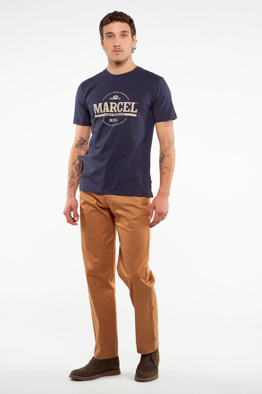 Bruine kostuumbroek van Le Fabuleux Marcel de Bruxelles, gedragen met een donkerblauw T-shirt en kaki laarzen.