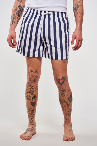 Blauwe gestreepte zwembroek van Le Fabuleux Marcel de Bruxelles, met tatoeages op de benen en armen.