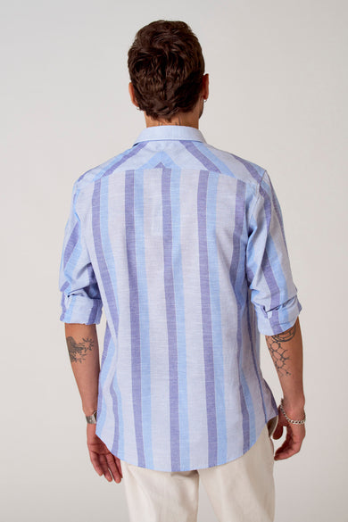 Blauw gestreept overhemd van Le Fabuleux Marcel de Bruxelles, achterkant gezien met opgerolde mouwen en tatoeages.
