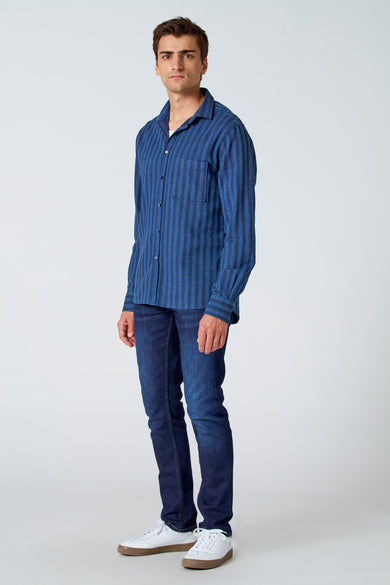 Blauw gestreept overhemd met lange mouwen van Le Fabuleux Marcel de Bruxelles, gedragen met donkere jeans en witte sneakers, volledige weergave.
