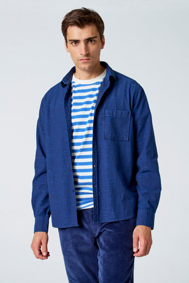 Blauw overhemd met lange mouwen van Le Fabuleux Marcel de Bruxelles, gedragen over een gestreept T-shirt met blauwe corduroy broek.