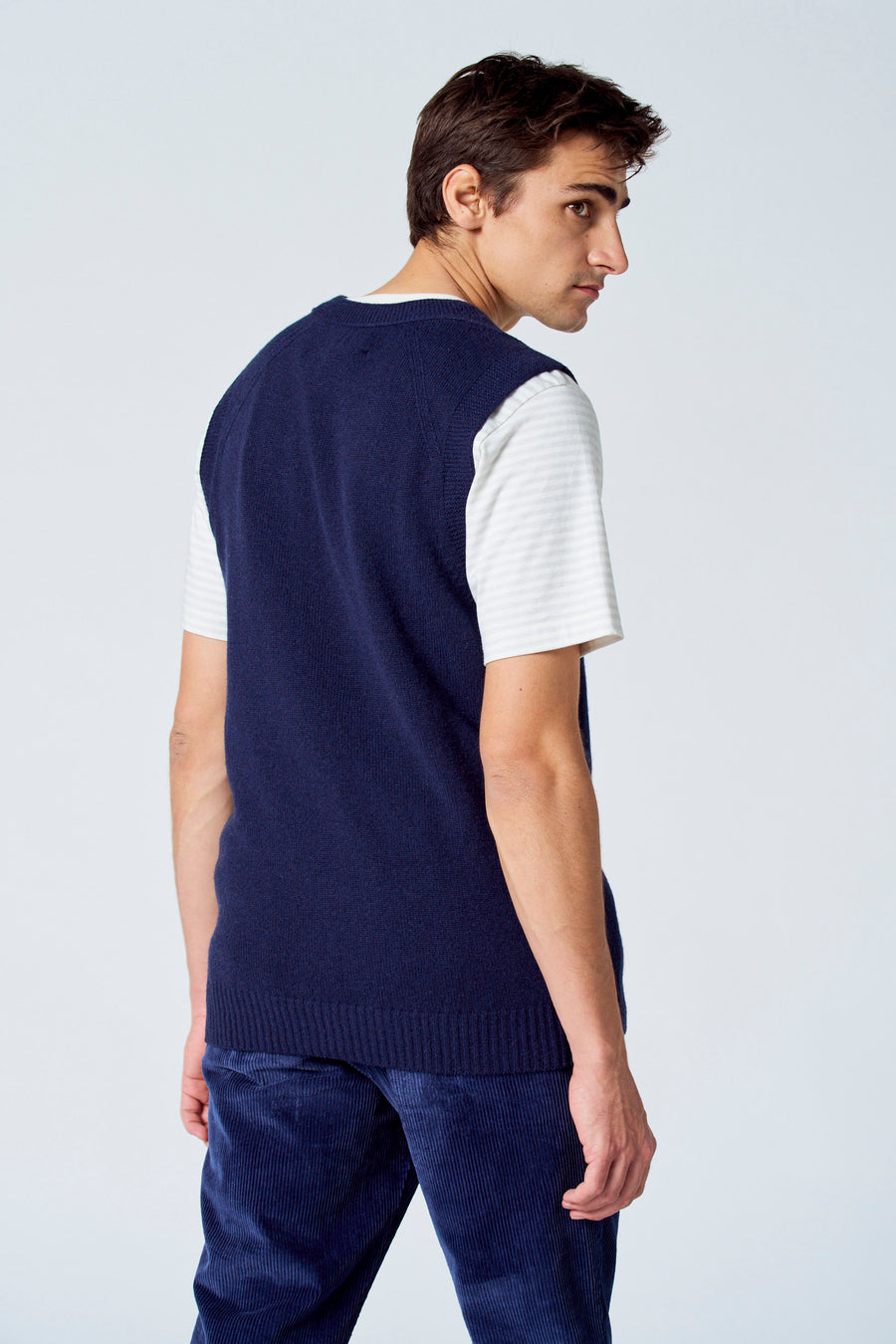 Blauw debardeur van Le Fabuleux Marcel de Bruxelles, gedragen over een gestreept shirt en ribfluwelen broek.
