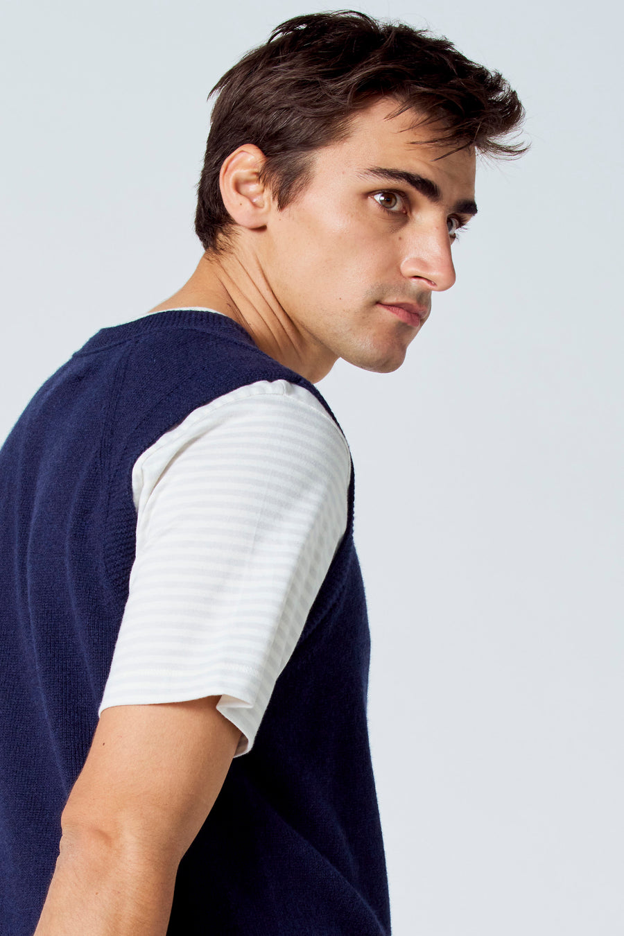 Blauwe debardeur van Le Fabuleux Marcel de Bruxelles, gedragen over een gestreept shirt, op een close-up zijwaartse foto.
