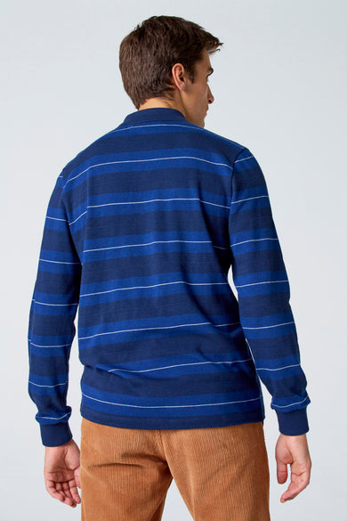 Blauwe polo met lange mouwen van Le Fabuleux Marcel de Bruxelles, gestreept met witte accenten, op bruine corduroy broek.