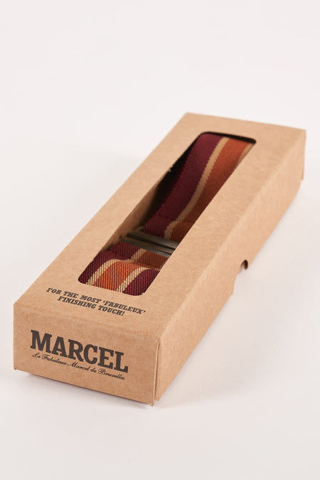 Multicolour riem van Le Fabuleux Marcel de Bruxelles in een kartonnen doos met gestreept patroon.

