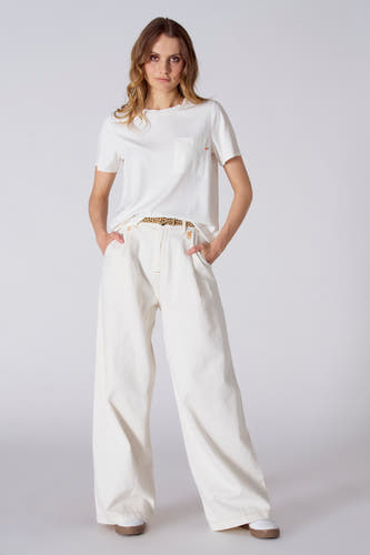 Pantalon blanc de Le Fabuleux Marcel de Bruxelles, avec des jambes larges, associé à un T-shirt blanc et une ceinture imprimée zèbre.