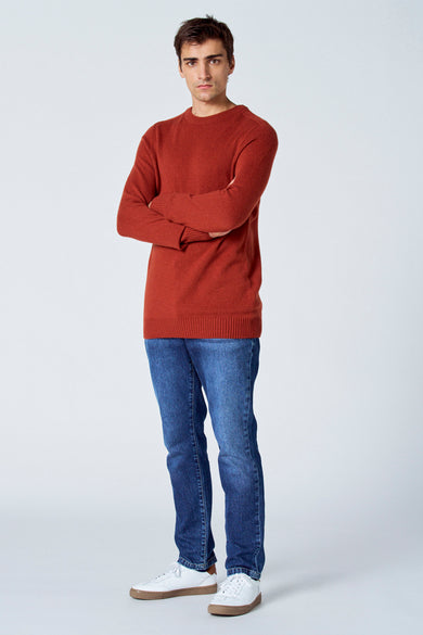 Bordeaux trui met ronde hals van Le Fabuleux Marcel de Bruxelles, gecombineerd met jeans en witte sneakers.
