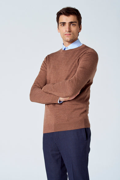 Pull marron avec col rond de Le Fabuleux Marcel de Bruxelles, porté sur une chemise bleu clair, avec un pantalon bleu marine.