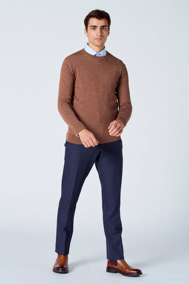Pull marron avec col rond de Le Fabuleux Marcel de Bruxelles, porté avec un chemise bleu et un pantalon bleu marine avec des chaussures marrons.