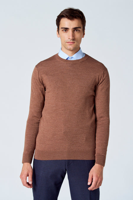 Bruine trui met ronde hals van Le Fabuleux Marcel de Bruxelles, gedragen over een lichtblauw overhemd, met donkerblauwe pantalon.