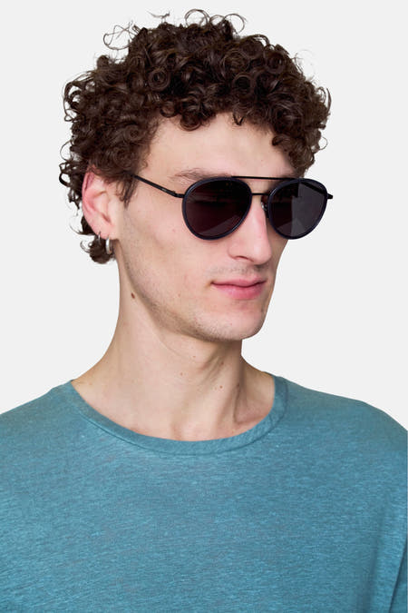 Lunettes de soleil bleues de Le Fabuleux Marcel de Bruxelles, avec un cadre fin noir et des verres ronds.