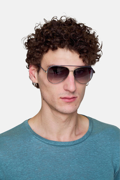 Zilveren zonnebril van Le Fabuleux Marcel de Bruxelles, gedragen door een model met een turquoise t-shirt en zilveren oorbellen.
