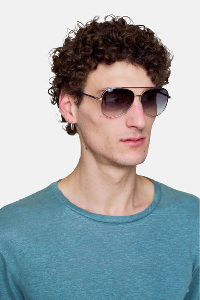 Zilverkleurige zonnebril van Le Fabuleux Marcel de Bruxelles, gedragen door een persoon met krullend haar en een blauwgroen shirt.