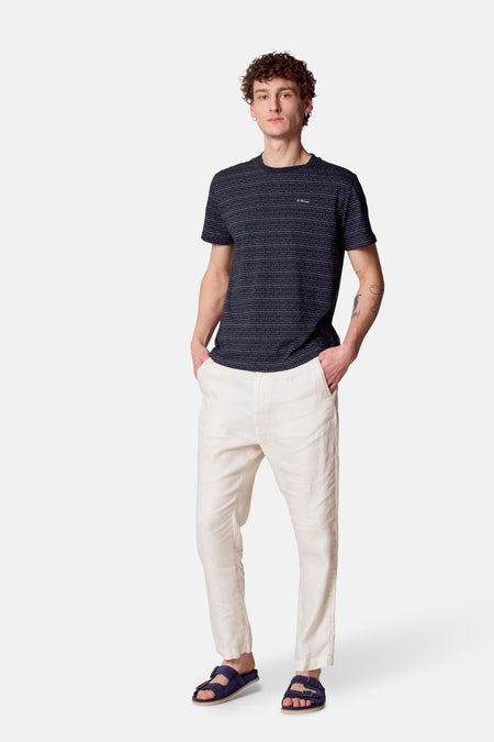 Man met gestreept t-shirt, linnen broek en blauwe sandalen.
