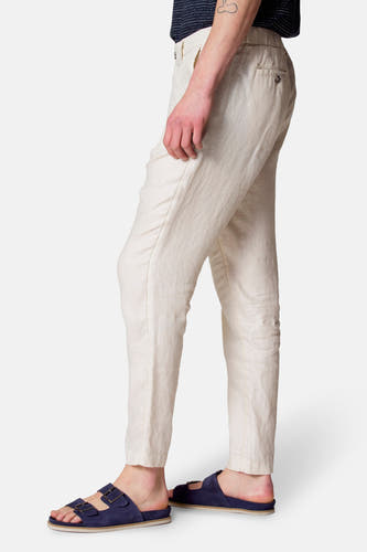 Pantalon beige Le Fabuleux Marcel de Bruxelles, vu du côté, avec une texture subtile et des sandales décontractées.