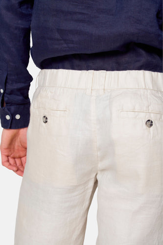 Donkerblauw linnen overhemd, crèmekleurige linnen broek met knoopsluiting, achterkant.
