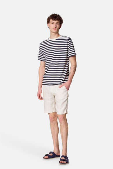 Blauw gestreept T-shirt met korte mouwen van Le Fabuleux Marcel de Bruxelles, gedragen met lichte shorts en sandalen.
