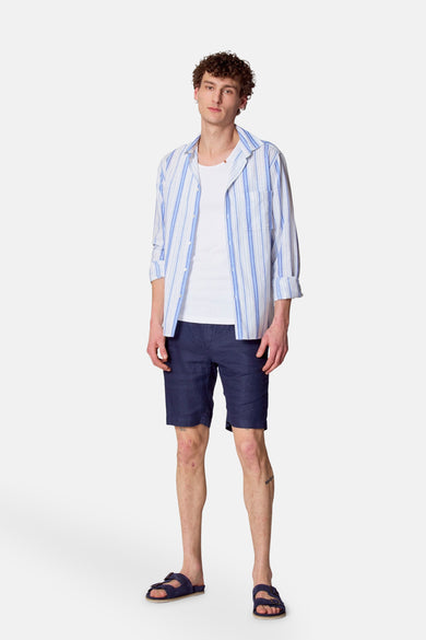 Blauw overhemd met lange mouwen van Le Fabuleux Marcel de Bruxelles, met blauwe en witte strepen, gedragen over een wit T-shirt.