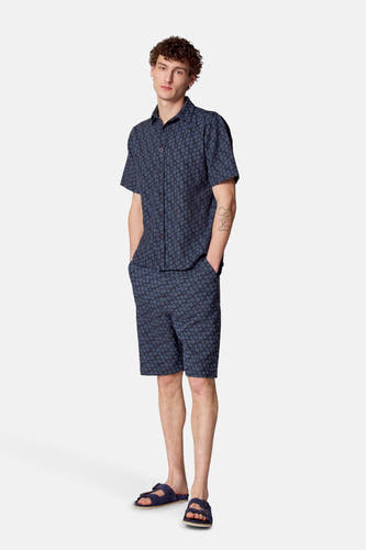 Blauw bloemen overhemd van Le Fabuleux Marcel de Bruxelles, met bijpassende shorts en blauwe sandalen.
