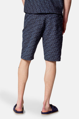 Blauwe bloemenprint shorts met blauwe slippers.
