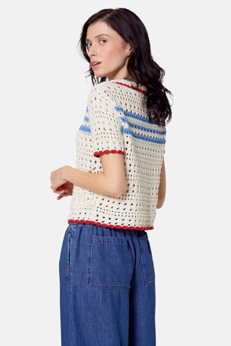 Beige trui met korte mouwen van Le Fabuleux Marcel de Bruxelles, met blauwe en rode strepen en wijde denim broek.
