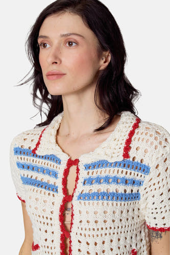 Pull beige avec chemise de Le Fabuleux Marcel de Bruxelles, avec des détails bleus et rouges et une texture ouverte.