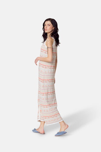 Multikleurige mouwloze jurk van Le Fabuleux Marcel de Bruxelles, met een horizontaal gestreept patroon, gedragen met blauwe slippers.
