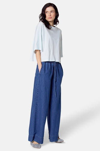 T-shirt bleu clair à manches courtes de Le Fabuleux Marcel de Bruxelles, porté avec un pantalon de denim large et des chaussures imprimées zèbre.