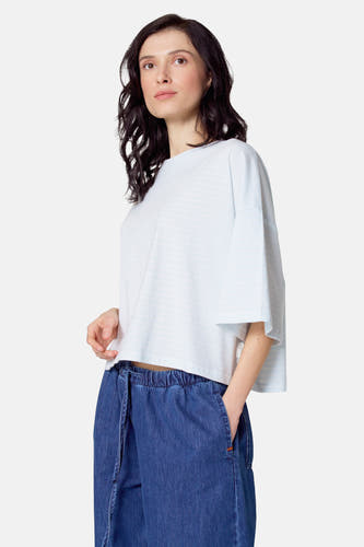 T-shirt rayé bleu clair de manches courtes de Le Fabuleux Marcel de Bruxelles, porté avec un pantalon bleu à cordon.