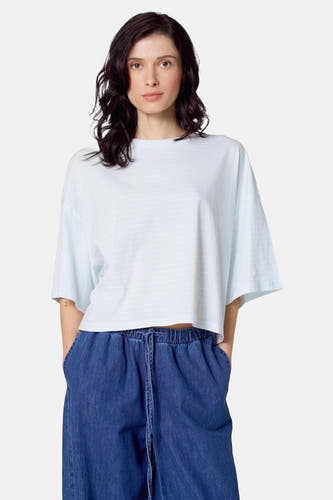 T-shirt bleu clair à manches courtes de Le Fabuleux Marcel de Bruxelles, avec un motif rayé subtil, porté avec un pantalon bleu marine.