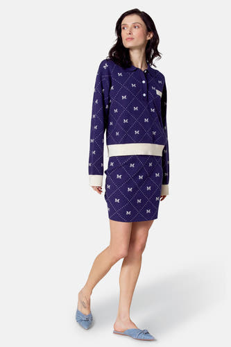 Jupe courte bleue de Le Fabuleux Marcel de Bruxelles, avec un motif 'M' sur toute la surface et associée à une chemise coordonnée.