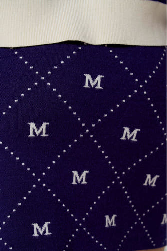 Jupe courte bleue de Le Fabuleux Marcel de Bruxelles, avec un motif 'M' blanc et des carreaux à pois.
